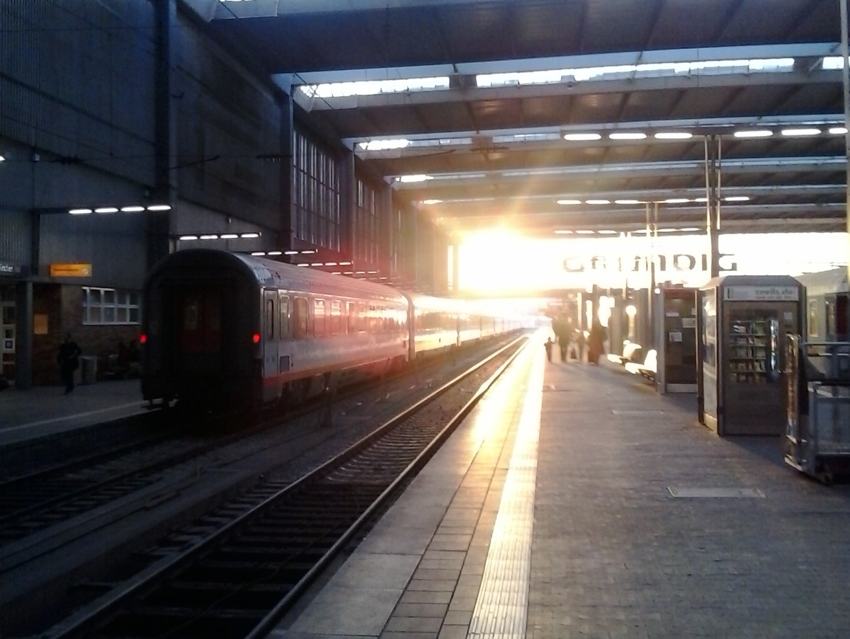 Gleisbett mit herausfahrendem Zug umgeben von Sonnenstrahlen im Hauptbahnhof München
